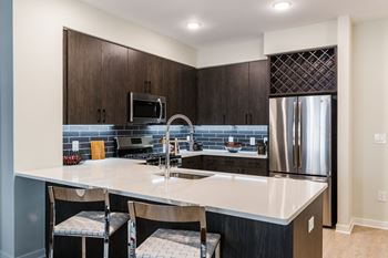A kitchen with a large island and a stainless steel refrigerator